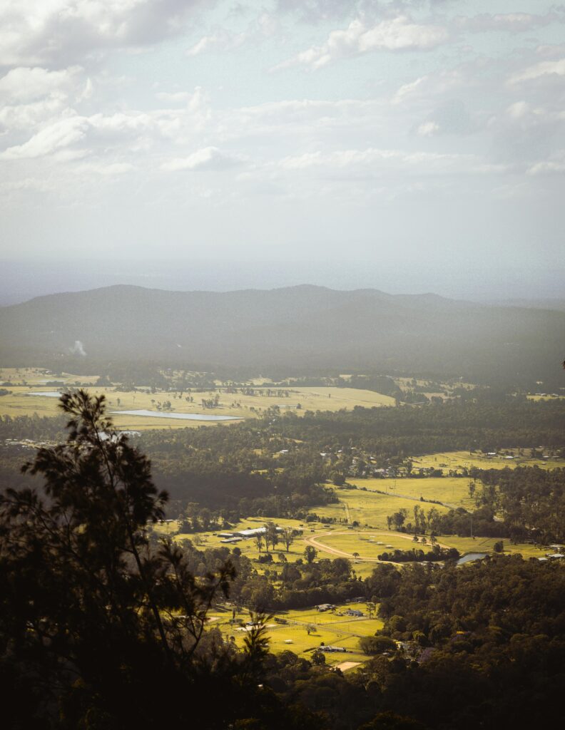 A high-angle view of a lush valley surrounded by mountains under a cloudy sky.